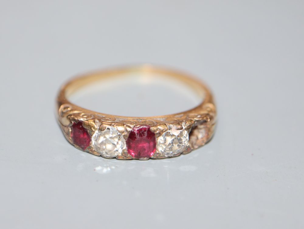 An early 20th century yellow metal, two(ex three) stone ruby and two stone diamond half hoop ring, size H, gross 3.1 grams.